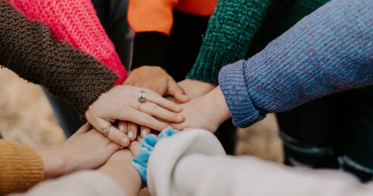 Team member hands joined together for a cheer.