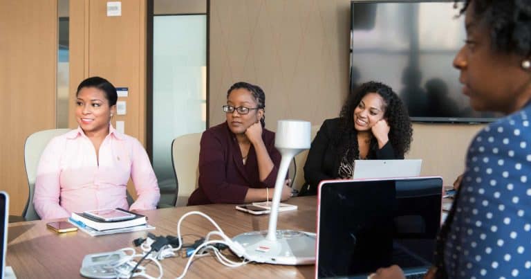 Women around conference table watching presentation.