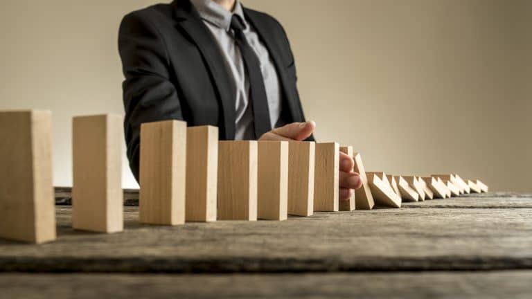 A businessman stopping dominoes from from falling.