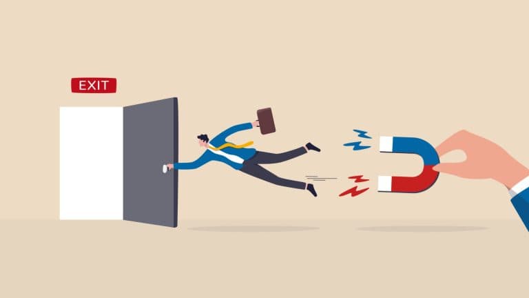A businessman heading for the door is being pulled back by a magnet.