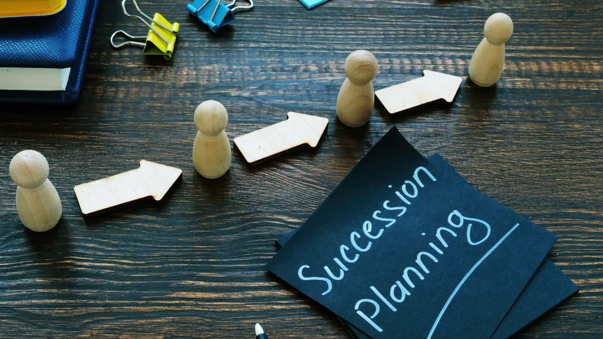 Succession planning sign and figurines with arrows.