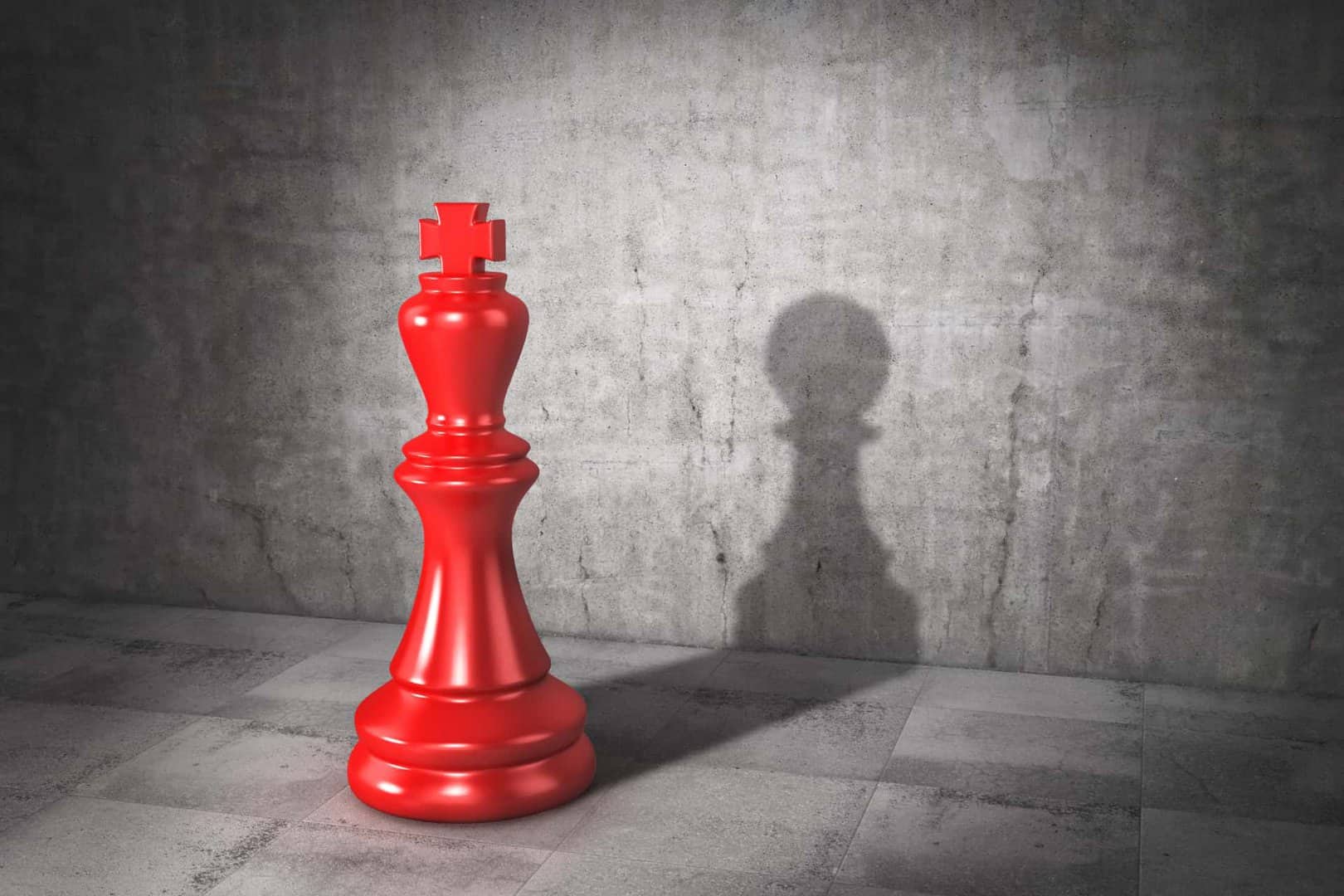 A large red chess king stands on a tiled floor casting a pawn shadow against a gray concrete wall.