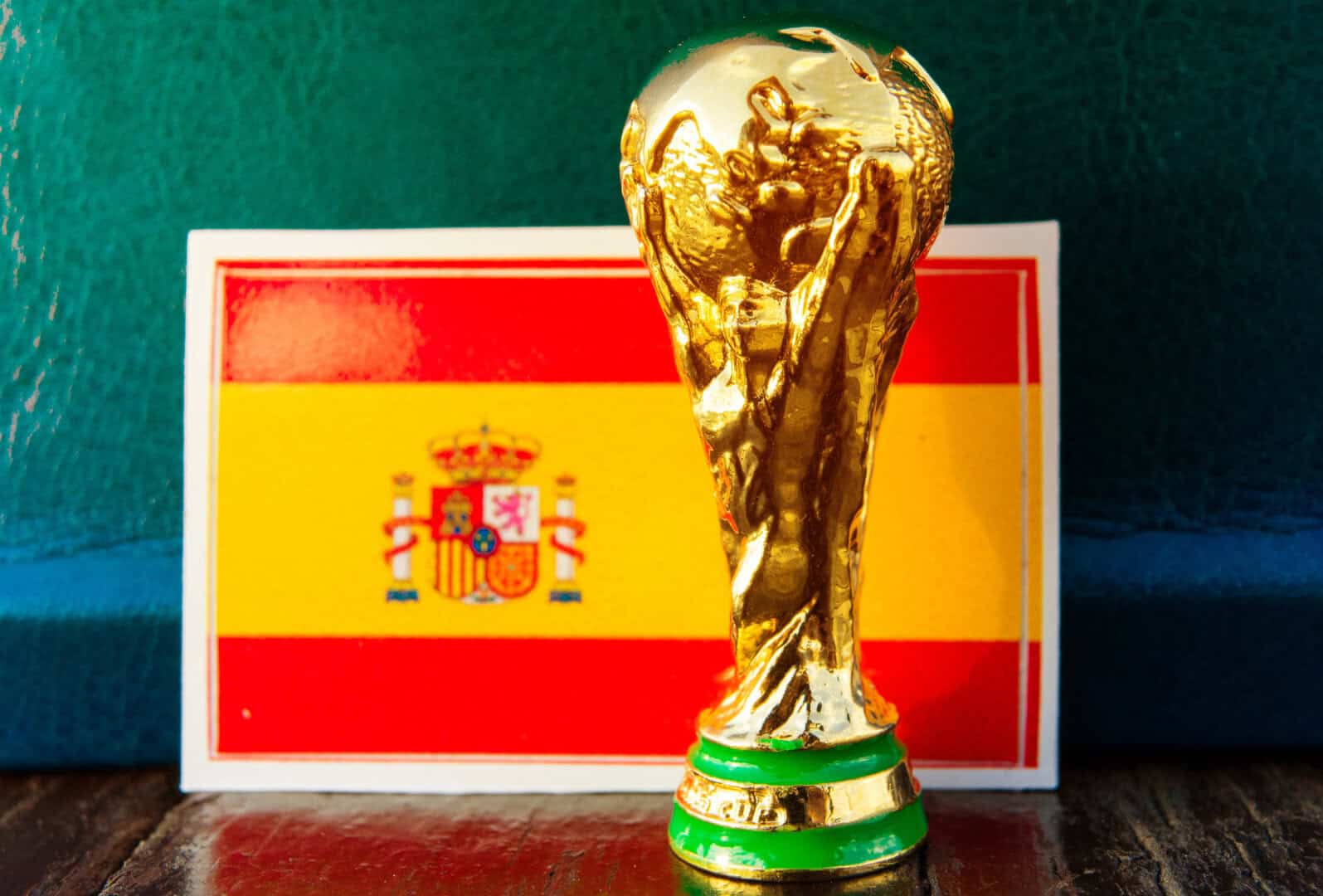A small FIFA World Cup trophy replica is placed in front of a card displaying the flag of Spain